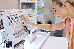 confident seamstresses in modern studio workshop, preparing tailoring machine for work