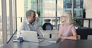 Confident senior business woman talking to younger colleague