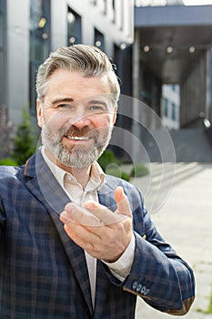 Confident senior businessman extending handshake outside modern office building