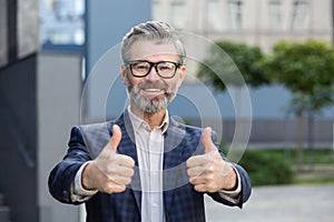 Confident senior businessman giving thumbs up outside the office building