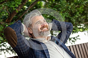 Confident senior businessman relaxing outdoors in a stylish suit and smiling