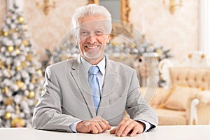 Confident senior businessman sitting at table at home
