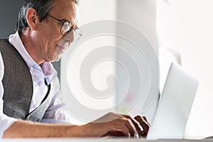 Confident senior businessman sitting at table with notebook