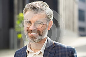 Confident senior businessman smiling in front of office building in a stylish suit