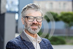 Confident senior businessman smiling in front of office building wearing suit