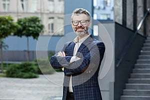 Confident senior businessman in suit standing outside modern office building