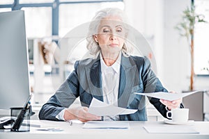 Confident senior businesswoman doing paperwork at workplace