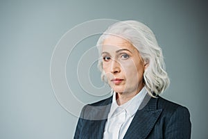 Confident senior businesswoman in suit on grey