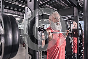 Confident senior man is doing sport in modern gym