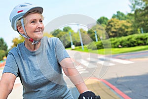 Confident senior woman smiling while riding bicycle in park