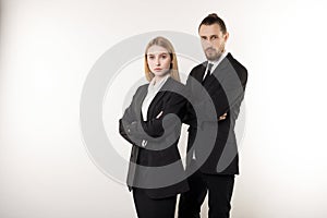 Confident serious businesspeople posing in black suits, standing with crosed hands, looking at camera