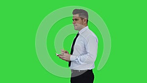 Confident serious smart businessman having an idea and making notes on a Green Screen, Chroma Key.