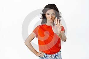 Confident serious woman say no, extend hand to make stop, block sign, prohibit, tell to keep away, remain distance