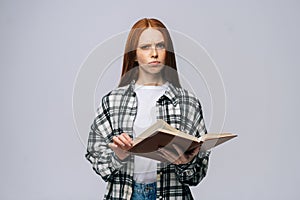 Confident serious young woman college student holding opened books and looking at camera
