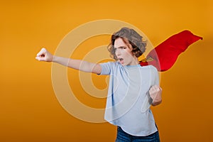 Confident short-haired girl posing in red superhero cloak. Studio shot of brave young woman in superwoman costume..