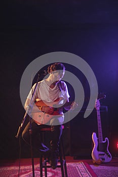 Confident singer playing guitar while performing in concert