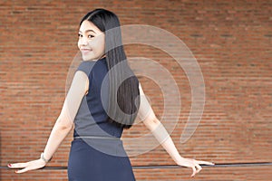 Confident and Smart Asian woman turning around with red brick wall interior.