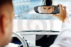 Confident smart man looking into the rearview mirror