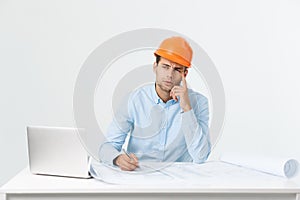 Confident smiling architect in formal wear thinking and working with blueprint papers and drawings in modern lightful