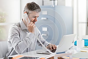 Confident smiling businessman and consultant working in his office, he is having a phone call: communication and business concept photo