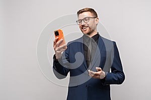 Confident smiling businessman having online conversation on smartphone on grey background.