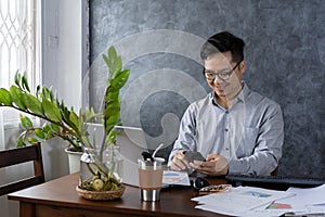 Confident smiling businessman using smartphone in a home office. Checking new e-mails