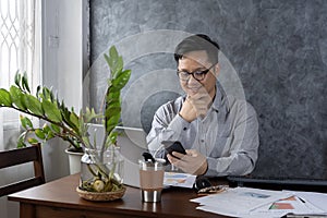Confident smiling businessman using smartphone in a home office. Checking new emails. Inspiring productivity with a wealth of