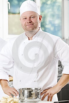 Confident and smiling chef standing in large kitchen