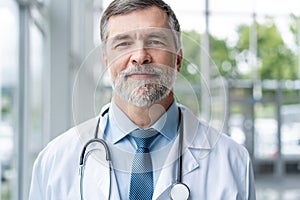 Confident smiling doctor posing in the hospital with medical team working on the background.