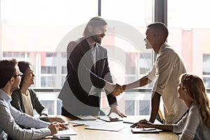 Confident smiling executive shaking African American employee hand at meeting