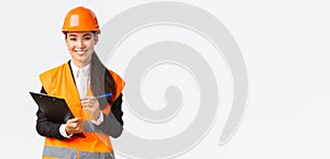 Confident smiling female asian construction engineer, industrial woman in safety helmet visit building area for