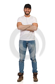 Confident Smiling Man In Black Cap Is Standing With Arms Crossed