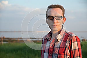 Confident smiling mature man looking at camera outdoor at a coast. Close up portrait.