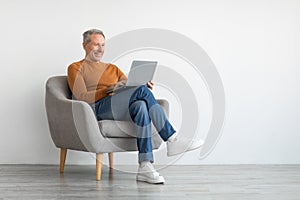 Confident smiling mature man using laptop at home