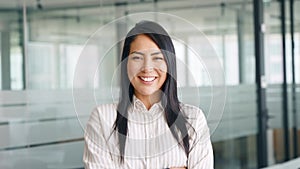 Confident smiling young Asian business woman standing in office, portrait.