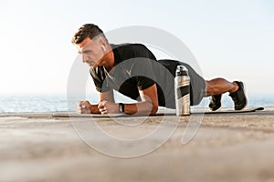 Confident sportsman in earphones doing plank