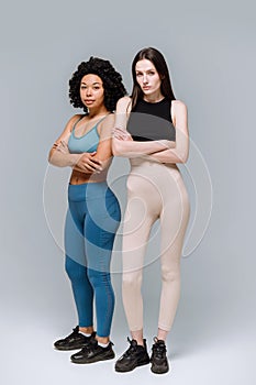 Confident sporty women standing in activewear isolated on gray background