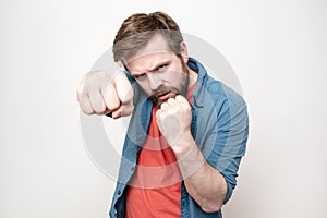 Confident, strong man clenched big fists, looked fearlessly and was about to defend himself, on a white background