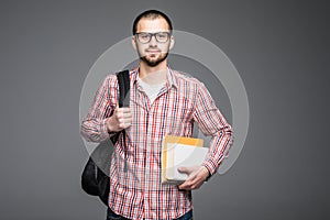 Confident student. Studio portrait of handsome young man holding books isolated on gray