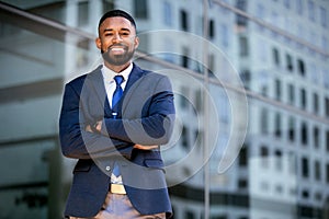 Confident successful african american businessman standing with arms folded, smiling, downtown financial district