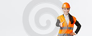 Confident successful female architect, leader of construction in safety helmet, reflective jacket, extand hand for