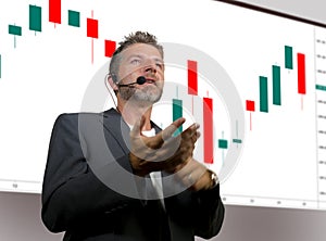 Confident successful trader man with headset speaking at event coaching trading business at auditorium or conference room teaching