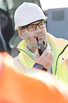 Confident supervisor using walkie-talkie at construction site
