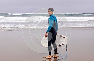 Confident surfer looking at sea before surfing, copy space