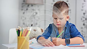 Confident talented cute little boy drawing picture using colorful pencil medium close-up