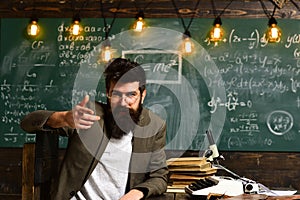 Confident teacher sit at desk. Businessman with beard in suit. Bearded man with typewriter, books and microscope