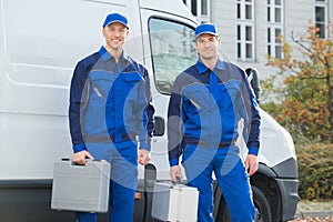 Confident Technicians Standing Against Truck