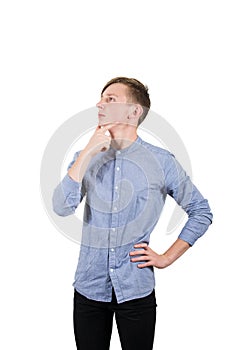 Confident teenage boy thinking, keeps one hand under chin and another on hips isolated over white background.
