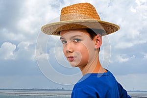 Confident teenager with straw hat at the beach photo