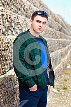 Confident trendy young guy against a stone wall